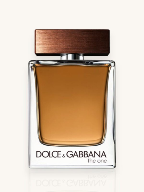 Dolce & Gabbana The One For Men Eau de Toilette 100 ml, flacone ambrato con tappo marrone fotografato in un ambiente raffinato con legno, foglie secche e luce calda.